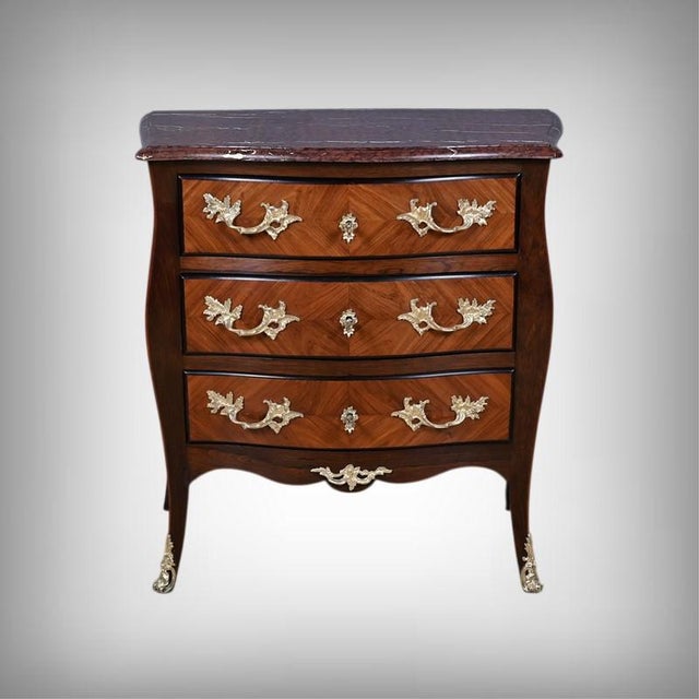 An elegant Parisian commode in the Transition style, crafted from marquetry, opening with three drawers in a curved front....