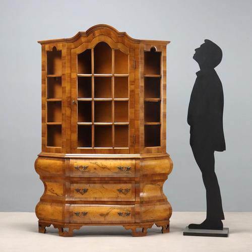 Walnut display cabinet with a trapezoidal cross-section. The top features a central door and glass sides, and a curved...