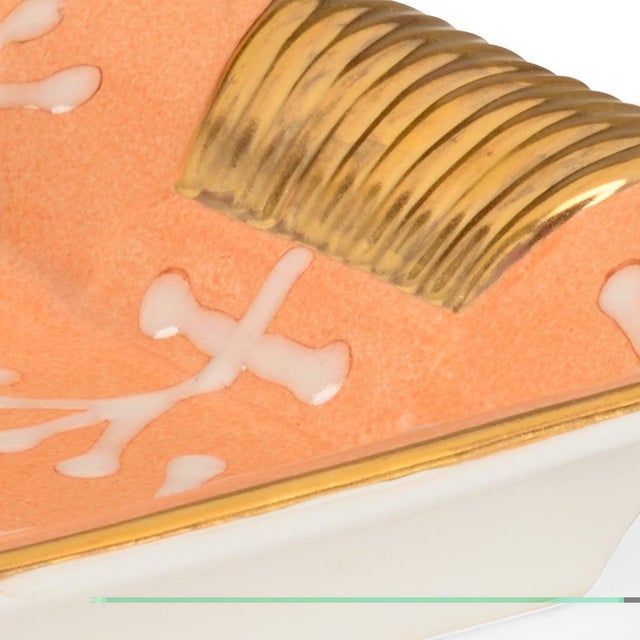 Pamela Tray features a hand painted cream pattern on a peach glazed porcelain tray with textured gold handles and trim....