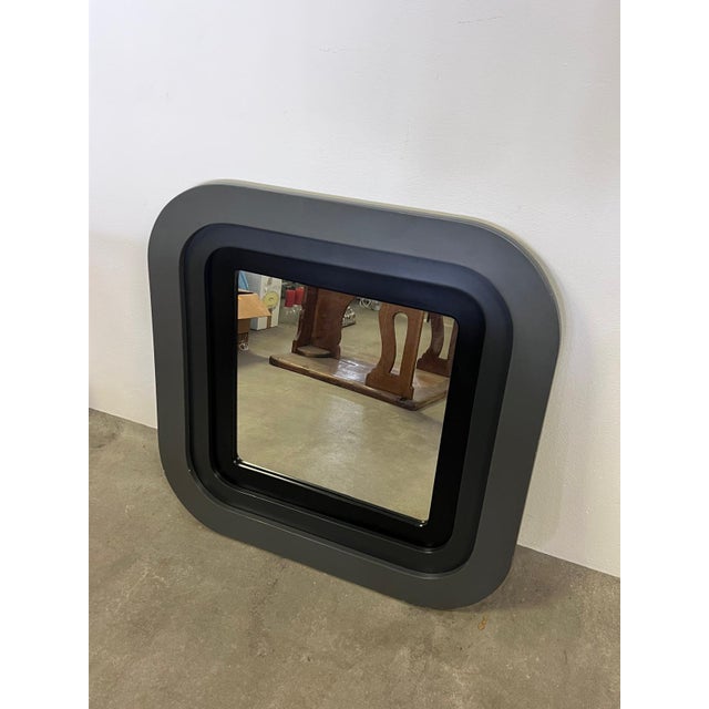 A 1970s-style mirror with a square shape and rounded corners. Made of gray/black lacquered wood. The unique pop-style...