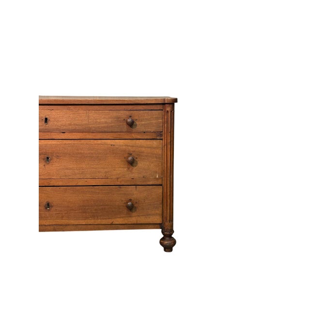 Elegant low walnut dresser with three drawers. The hand-crafted legs lend a sleek, refined feel to the frame, creating a...