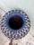 A substantial blue-glazed terracotta vessel enveloped in a hand-tied rattan lattice exterior that softens and grounds the...