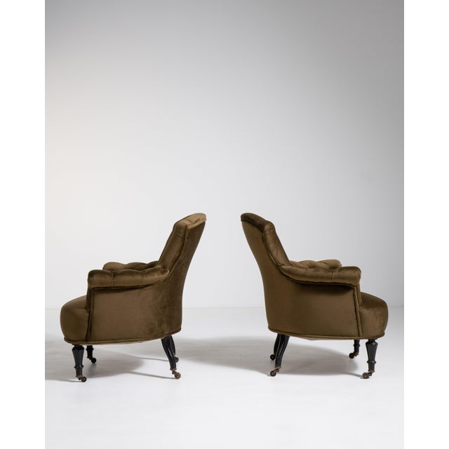 A luxurious pair of Napoleon III armchairs upholstered in velvet, emphasizing comfort and richness. The softly curved...