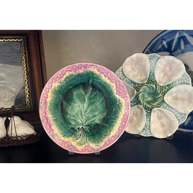 Majolica wall plate with pink basketweave background and a green maple leaf in the center. It was made by Griffin, Smith &...