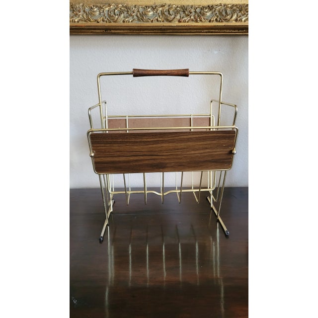 Rare find, MCM vintage magazine rack, from the 1950s to early 1960s, featuring a gold-tone metal frame with dark faux wood...