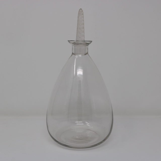 Rene Lalique clear glass 'Dornach' decanter. Has a bulbous shaped bottle. The clear and frosted glass stopper has a...