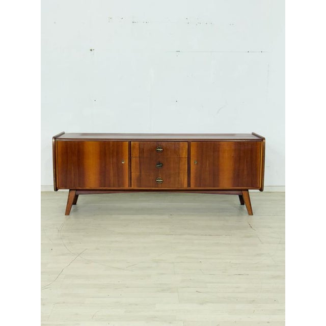 Beautiful, original vintage sideboard in a timeless mid-century design. The piece impresses with its warm wood grain,...