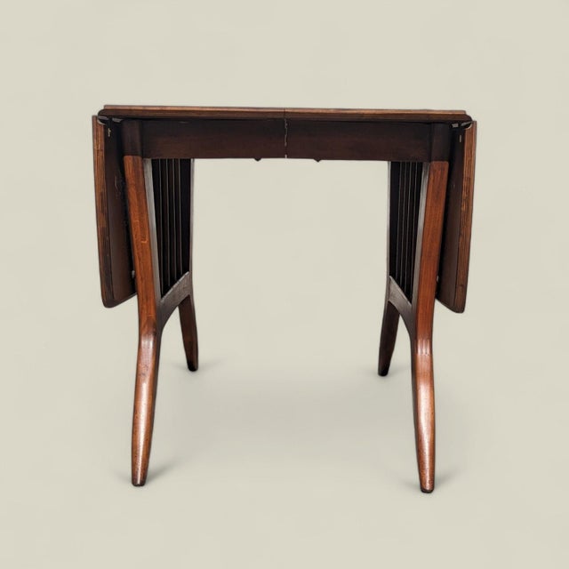 A vintage 1960s drop-leaf dining table by Garrison Furniture Co. featuring a warm wood base and durable laminate top. The...