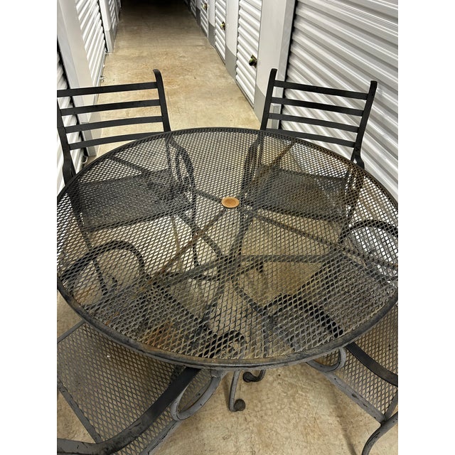 Lovely vintage wrought iron set with table and four chairs. Table has umbrella hole. Table is 47.5 inches in diameter and...