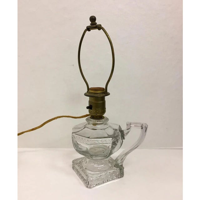 Precious antique electrified oil lamp from the early 20th century. The pressed glass lamp has a Greek key pattern and...