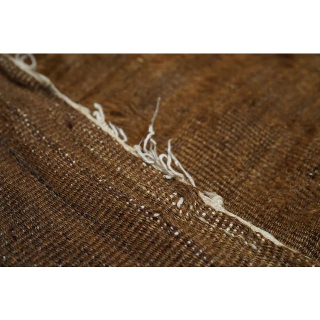 The particularly well-abrashed brown field shows wide and narrow ecru bands across the ends, and is centred by a fringed...