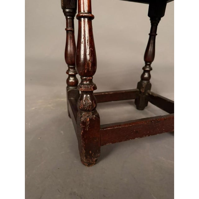 An authentic 18th-century English country oak low stool, circa 1780, featuring hand-turned legs and traditional mortise-...