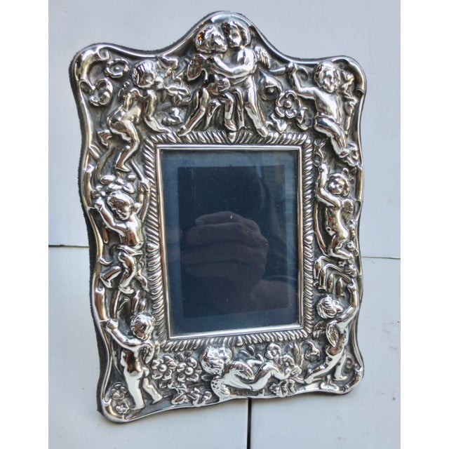 Sterling silver photo frame with Putti designs. Frolicking around the borders, the theme of love and romance is on...