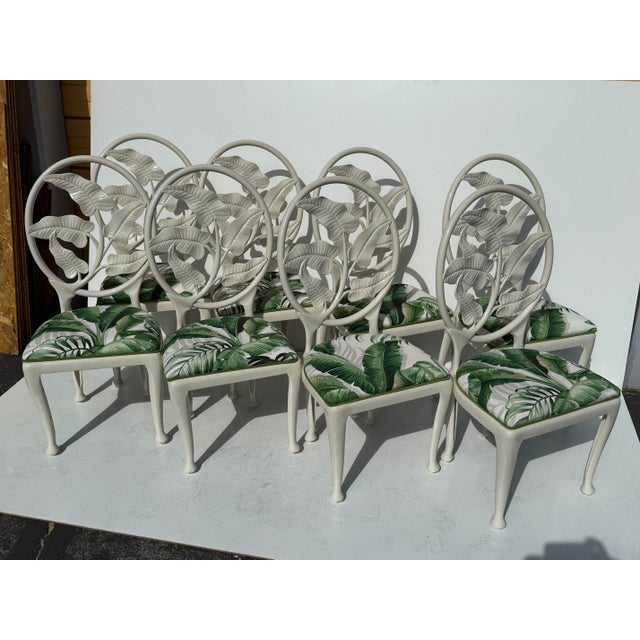 Set of eight cast aluminum tropical Palm Beach Regency patio chairs upholstered in banana leaf print fabric.