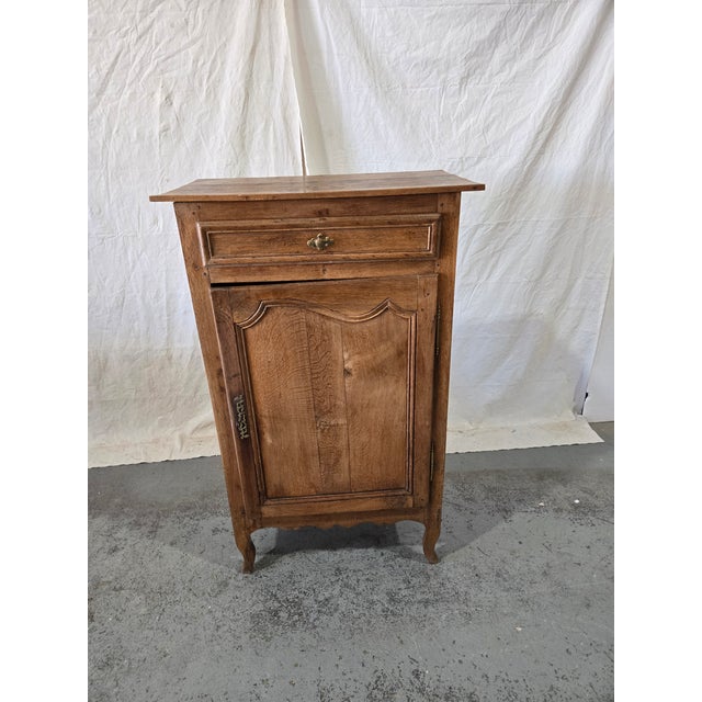 A charming 19th-century French provincial oak cabinet with Louis XV styling, featuring a single drawer above a paneled...