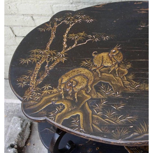 1920s two-tiered English table. Scalloped shaped table painted black with raised gold chinoiserie detail. Bird, goat,...