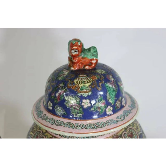 A stunning cobalt blue pair of famille rose Chinese porcelain ginger jars urns with Foo Dog covers, decorated with figures...
