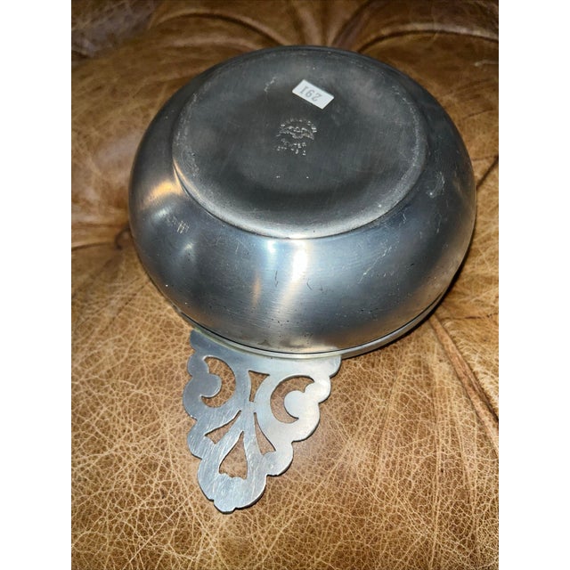 This 100% pewter porridge bowl with an intricate Gaelic decorated handle is marked on the bottom with its makers mark; the...
