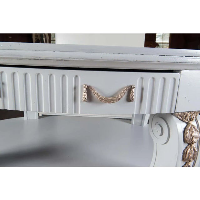 Grand light grey painted three-tiered oval center table with two large drawers. Original ormolu has been replated in a...