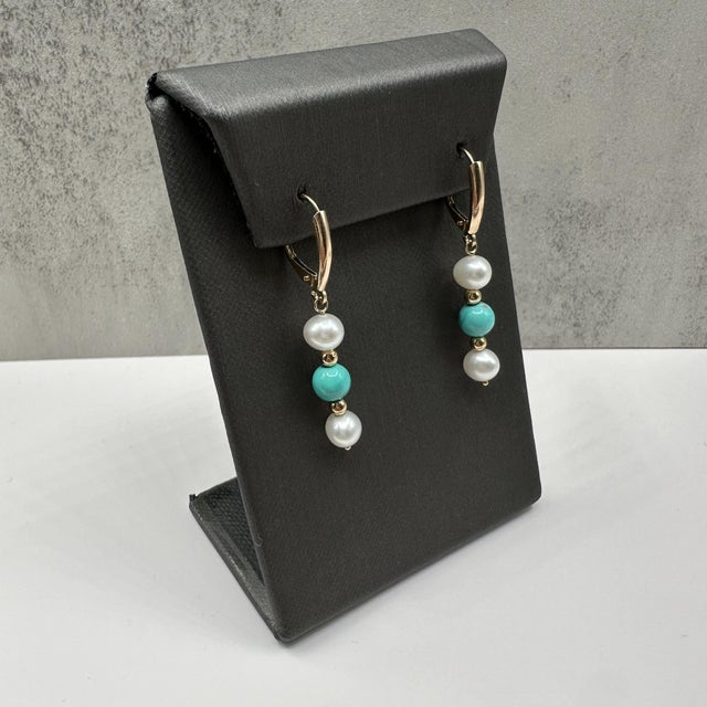 These elegant Turquoise and Pearl Drop Earrings in 14kt yellow gold feature (4) lustrous pearls and (2) vibrant turquoise...