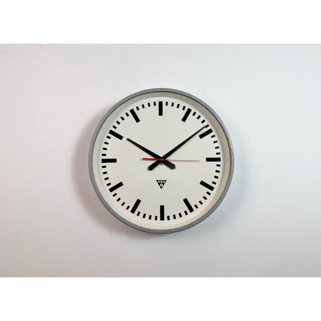 This wall clock was produced by Pragotron in former Czechoslovakia during the 1960s. It features a grey metal frame, an...