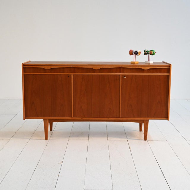 Teak sideboard with three doors and integrated upper drawers, clean lines and slender legs. Model "Primo", manufactured by...