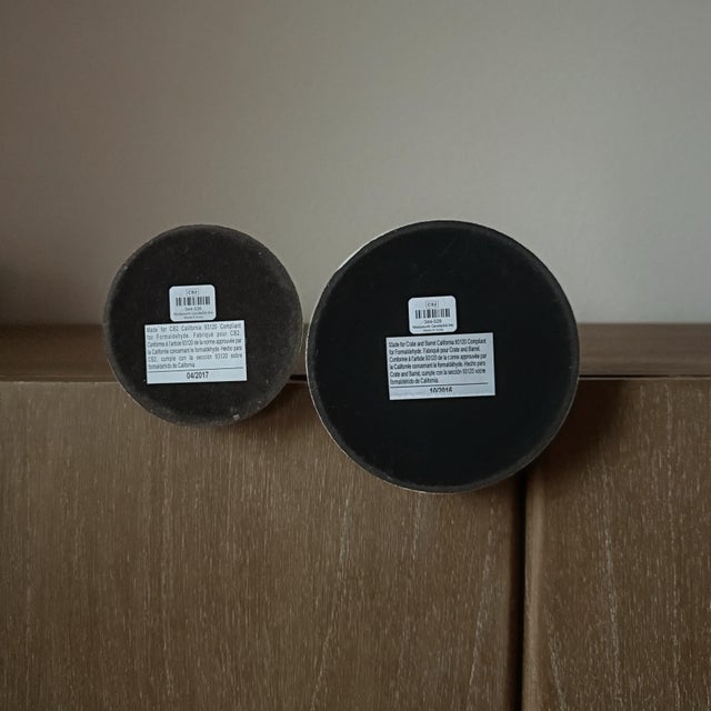 A sculptural graduated pair of CB2 Wadsworth taper candle holders in a warm white finish. The elongated silhouettes...