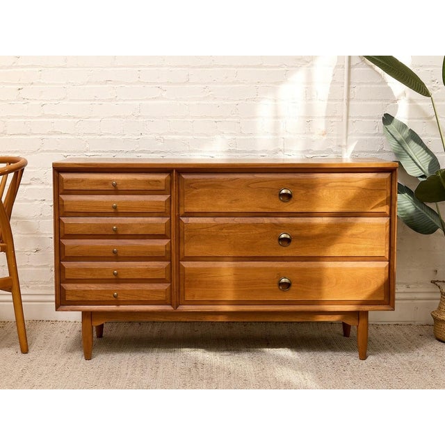 A handsome vintage mid-century dresser with a wonderfully asymmetrical layout and warm walnut finish. The left side...