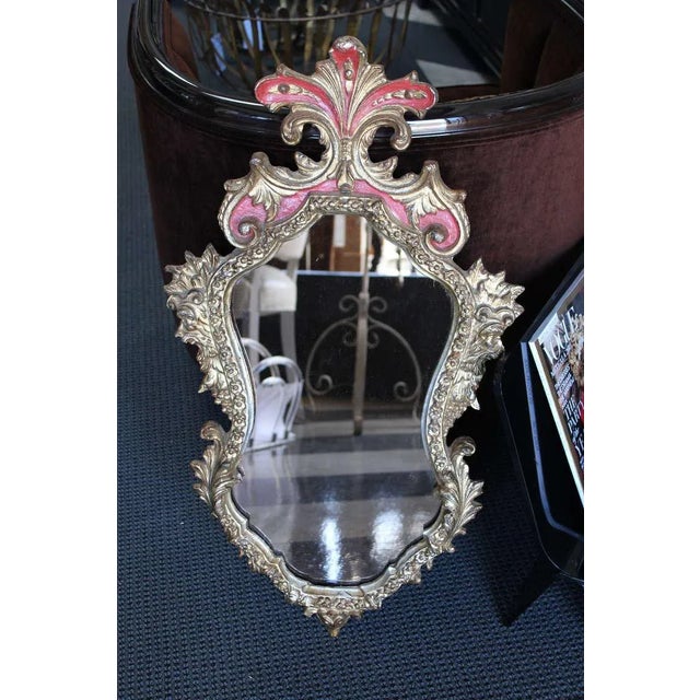 Charming Rococo inspired gilt and red painted, shaped frame. A Bronzy-rose tinted mirror was added for extra drama. This...