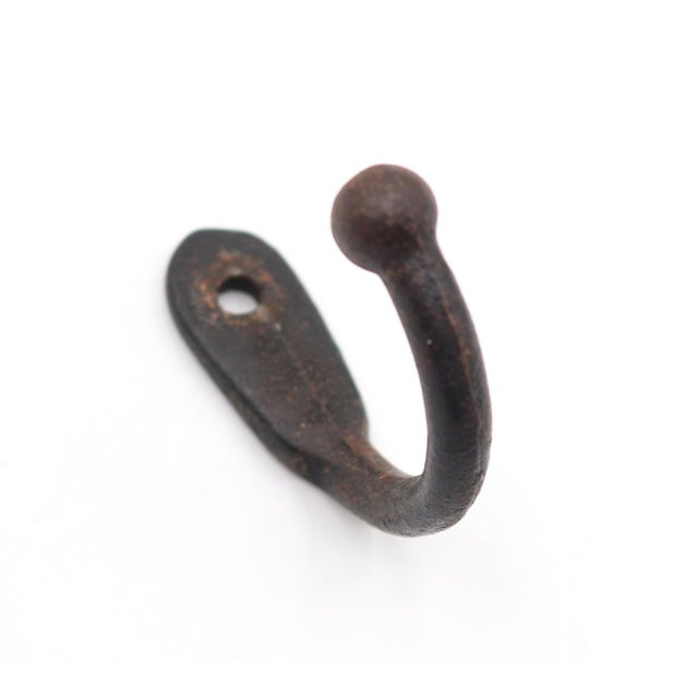 Vintage single arm black finished cast iron wall hook with a ball tip. The original mounting screws are not available....