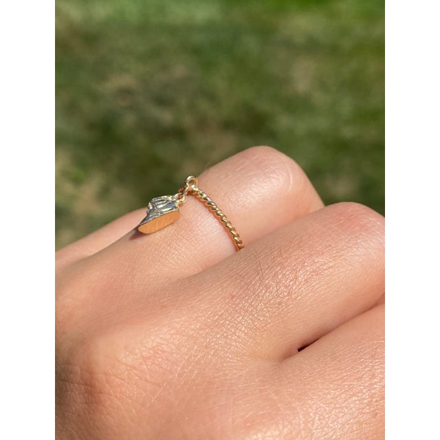 The Cape San Blas: Yellow Gold Baby Shoe Ring. The ring features a baby shoe that dangles on the top of the ring on a...