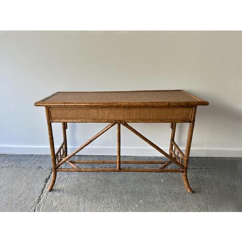 Vintage bamboo and rattan console table / writing desk in classic 1970s–1980s tropical / boho style. Features a woven cane...