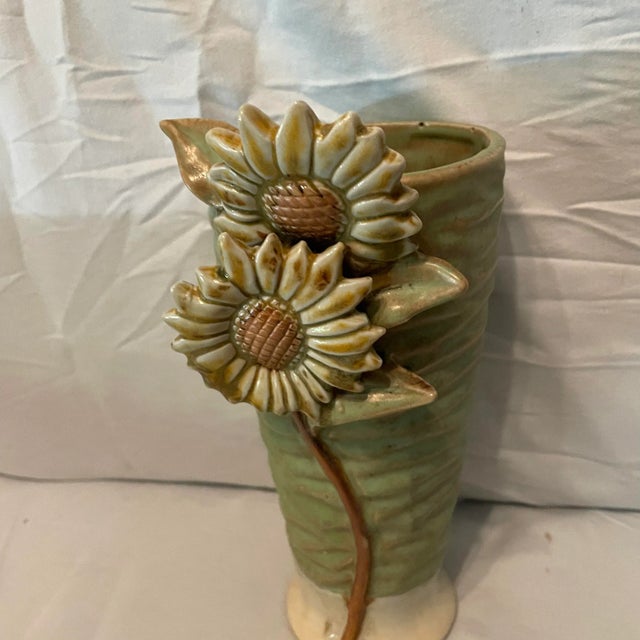 It appears to have a signature but, I can’t make it out. Lovely studio vase with raised sunflowers. There is a small chip...