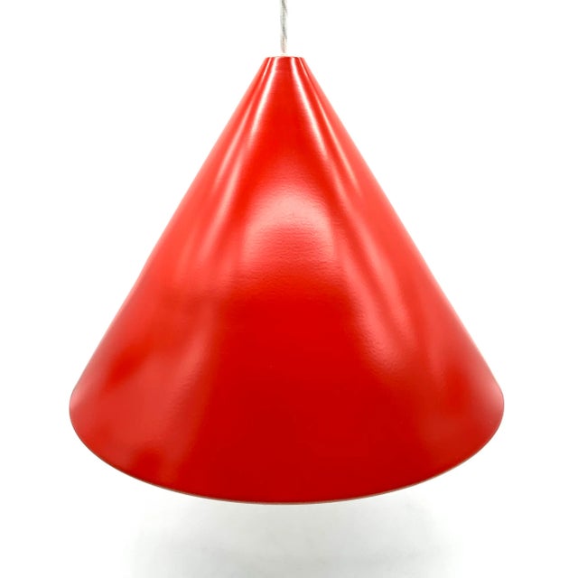 This bright orange-red Panton-style pendant lamp impresses with its clear, conical shape and timeless presence. The...