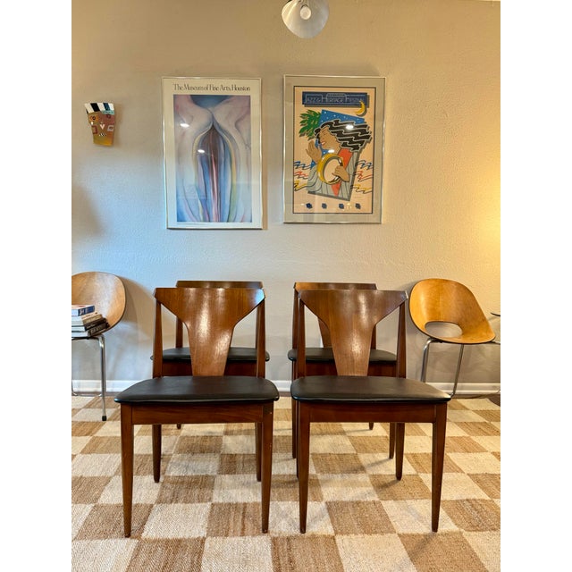 A beautiful set of 4 mid century modern dining chairs in teak with black faux leather seats, designed by Elliots of...