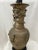 An antique bronze table lamp wrapped with raised dragons in relief circling the lamp. The Asian style lamp sits on a round...