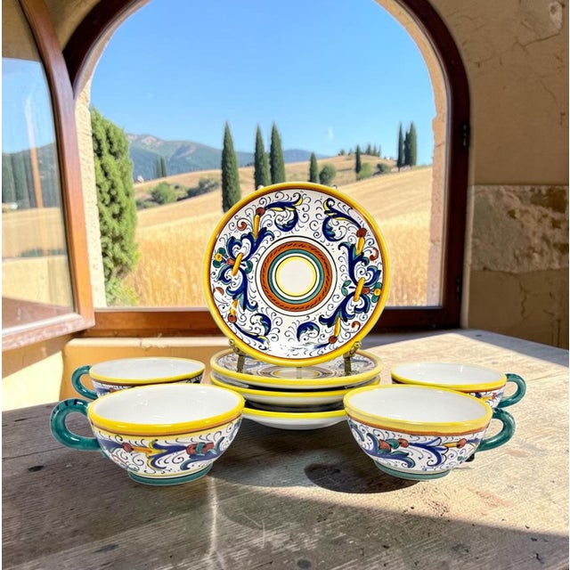 A coordinated set of four L.A.B.O.R. Deruta cups and matching saucers, hand painted in Deruta, Umbria, Italy, during the...