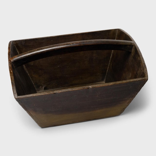 This rustic container is a traditional vessel used to measure and hold a dou of rice, an ancient Chinese unit of volume....
