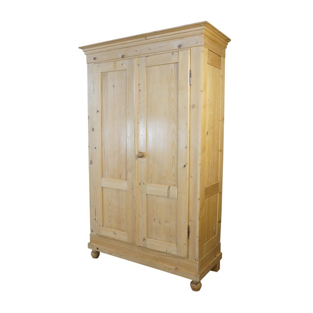 This antique European pine armoire or larder cupboard showcases a rustic, country-style aesthetic highlighted by its warm,...