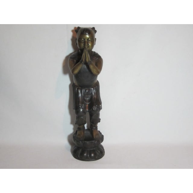 Asian boy standing on a lotus shaped base. It is made of brass with a antique brass and bronze finish.