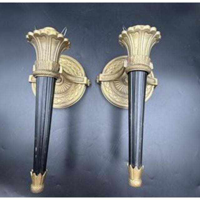 An exceptional and highly decorative pair of Neoclassical cast brass torch sconces, distinguished by their elegant...