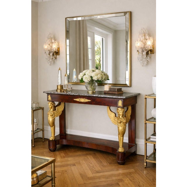 A VERY FINE FRENCH EMPIRE ORMOLU-MOUNTED MAHOGANY CONSOLE TABLE With polychromed winged sphinx supports Paris, France...