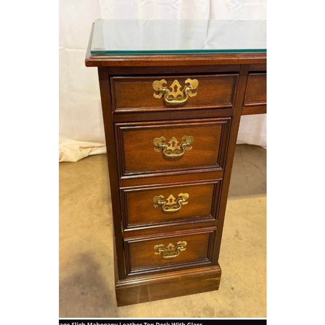 Vintage Sligh Mahogany Leather Top Partners Desk With Glass. The desk has 7 drawers with brass handles. It measures 30”Hx...
