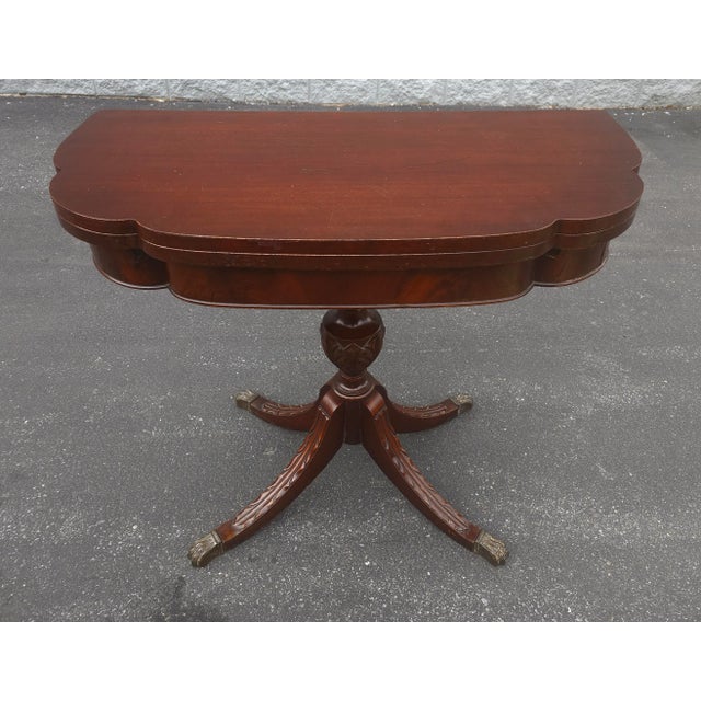 An Early 20th Century George III Style Mahogany Fold-Top Game Table Console Table with carved quad pod Pedestal and brass...