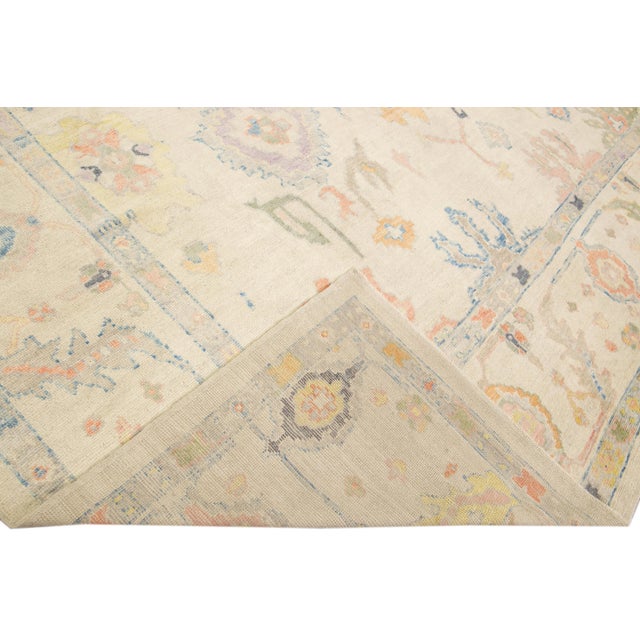 Beautiful modern Oushak hand-knotted wool rug with a beige field. This Oushak rug has multicolor accents all over a...