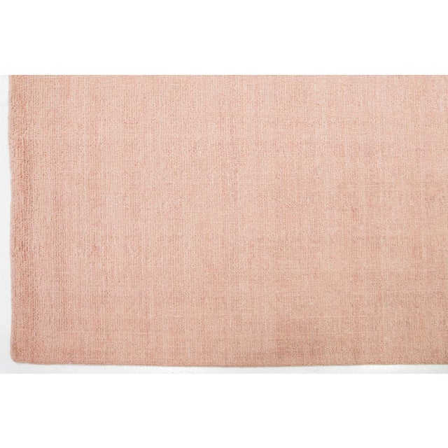 This modern Indian handknotted wool rug is skillfully woven by artisans and features a solid design. Its soft pink hue...