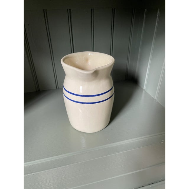Vintage stoneware pitcher in off white/cream glaze with blue stripe accent. Excellent condition.