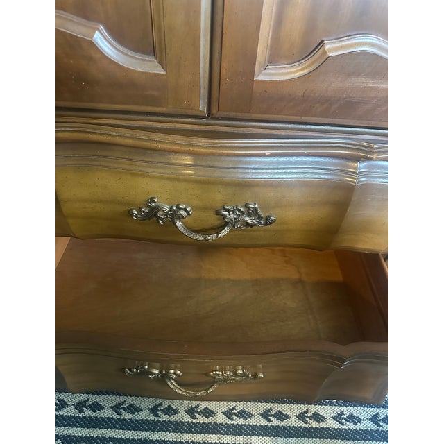 Elegant 1960s-era armoire in a classic French Provincial style. Featuring beautiful carved wood detailing, arched cabinet...
