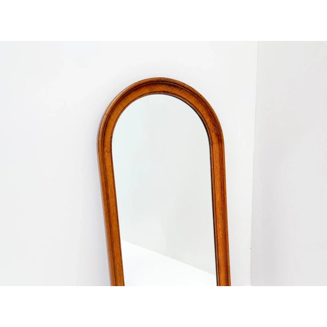 Vintage mid-century wall mirror with a solid wooden frame and an elegant rounded top. The light wood gives it a natural...