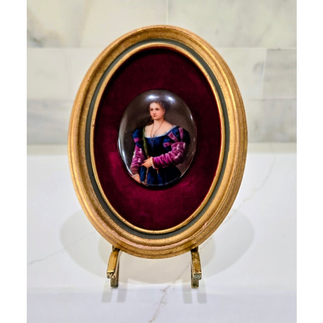 Elegant hand-painted porcelain portrait plaque after Titian’s “La Bella,” depicting a Renaissance beauty in richly colored...